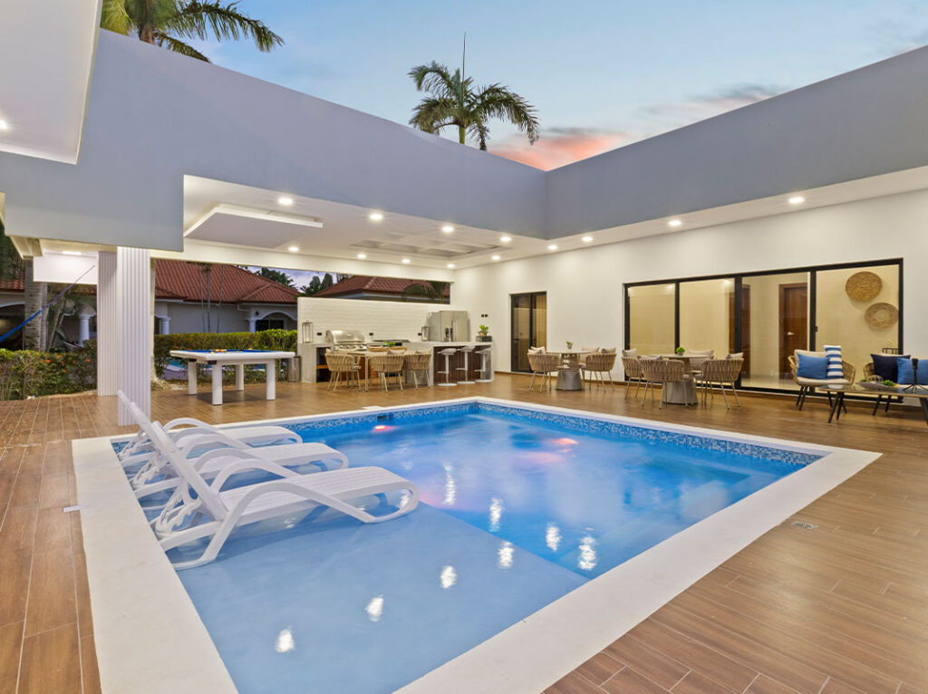 A sunken lounge area featuring a swimming pool surrounded by lounge chairs and dining furniture.